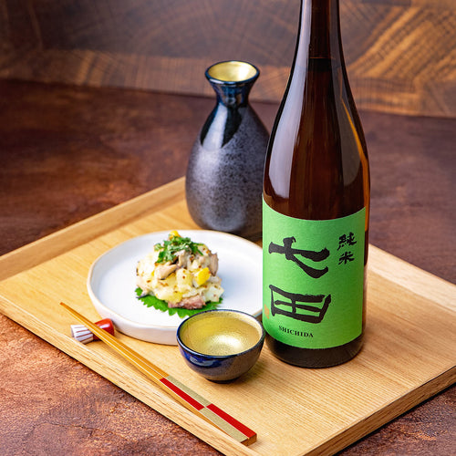 Shichida “Junmai” sake served with mackerel potato salad and the Mino no Takumi Black With Blue Drip Glaze And Gold Interior Sake Set, presented on a wooden tray.